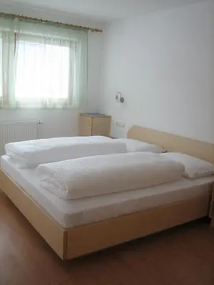 a bedroom with two beds with white sheets and a window at Garni - Appartement Neumairhof in Rasun di Sopra