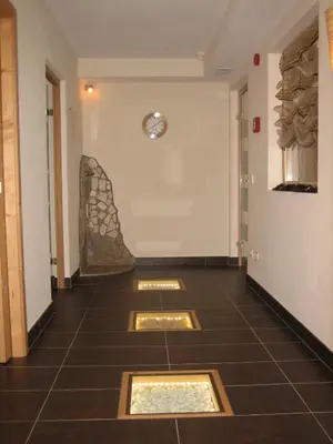 a hallway with a tile floor with a clock on the wall at Garni - Appartement Neumairhof in Rasun di Sopra