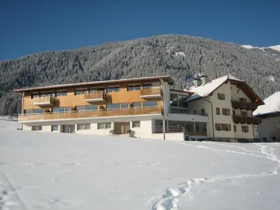 a building in the snow in front of a mountain at Garni - Appartement Neumairhof in Rasun di Sopra