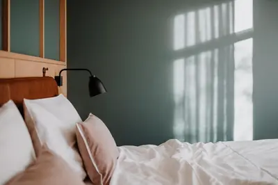 a bed with white sheets and pillows next to a window at VillaVerde Aparthotel in Lagundo