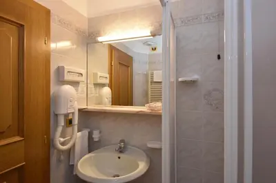 a bathroom with a sink and a shower with a mirror at Hotel San Marco in Passo San Pellegrino