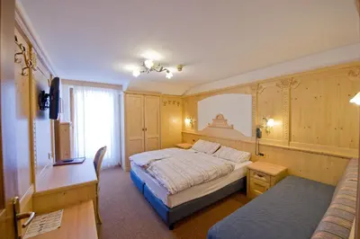 a bedroom with a bed and a desk and a couch at Hotel San Marco in Passo San Pellegrino