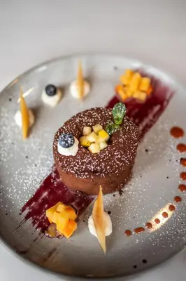 a plate with a chocolate doughnut with fruit on it at Hotel Fines in Funes