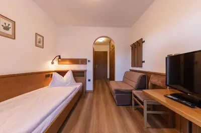 a hotel room with a bed and a chair and a tv at Hotel Fines in Funes