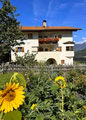 a building with a flower garden in front of it at Gasserhof in Barbiano