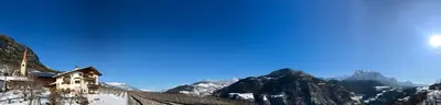 a building on a snowy mountain with mountains in the background at Gasserhof in Barbiano