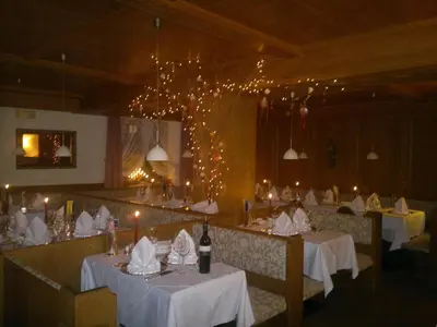 a dining room with tables with white tablecloths and lights at Hotel Ingram in Selva di Val Gardena