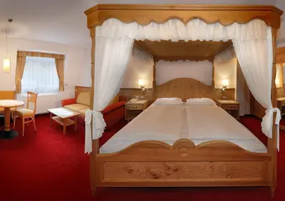 a bedroom with a canopy bed and a red carpet at Hotel Ingram in Selva di Val Gardena