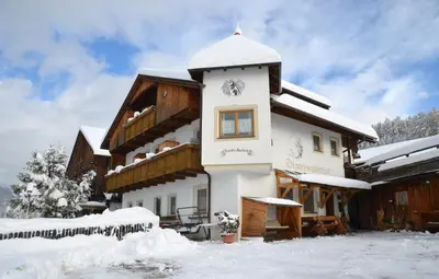 a building covered in snow with snow on the ground at Zimmer - Hinterwalderhof in Mühlbach