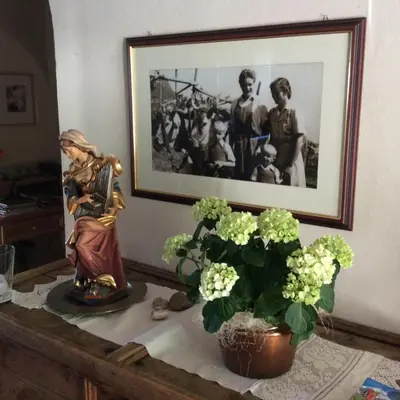 a statue and a plant on a table with a picture at Hotel Garni Paler in Tirolo