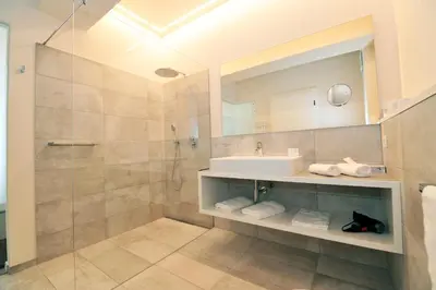 a bathroom with a shower and a sink and a mirror at Hotel Jasmin in Merano