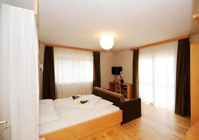 a bedroom with a white bed and a large window at Hotel Jasmin in Merano