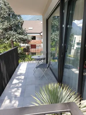 a patio with a table and a chair on a balcony at Hotel Jasmin in Merano