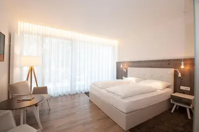 a bedroom with a large white bed and a table at Hotel Jasmin in Merano