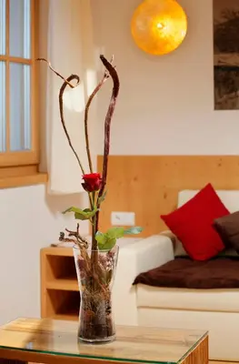 a vase with a rose sitting on a table at Schwarzplatterhof in Merano