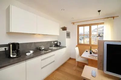 a kitchen with white cabinets and a table and a television at Schwarzplatterhof in Merano