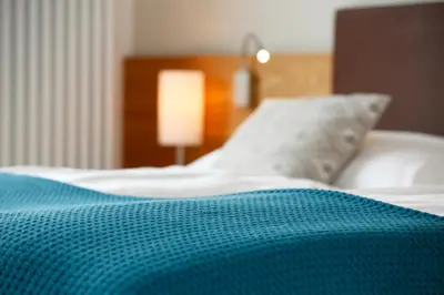 a bed with a blue blanket and a pillow at Landhaus Weger in Merano