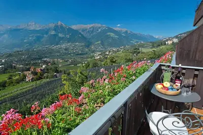 a bowl of fruit on a table on a balcony with flowers at Landhaus Weger in Merano