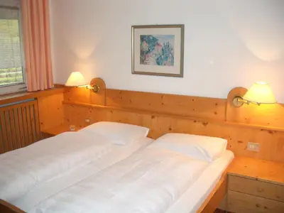 two beds in a bedroom with two lamps on the wall at Landhaus Weger in Merano