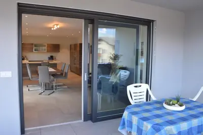 a sliding glass door with a table and a kitchen at Family Apartment Julia in Termeno