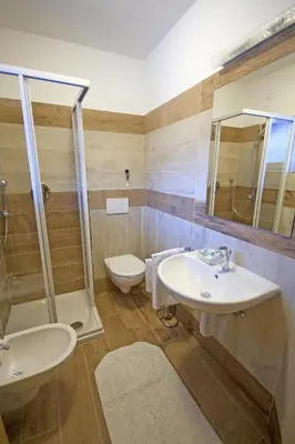 a bathroom with two sinks and a shower and a toilet at Hotel La Molinella in Soraga