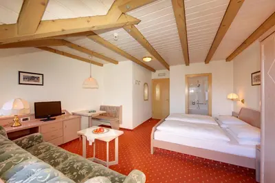 a bedroom with a large bed and a couch at Hotel Dolomitenblick in Collalbo