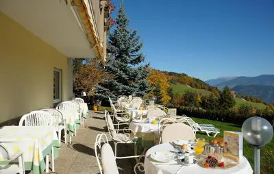 a group of tables with white chairs and a christmas tree at Hotel Dolomitenblick in Collalbo
