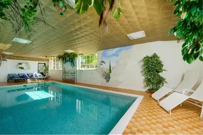 a swimming pool with two chairs and a table at Hotel Dolomitenblick in Collalbo