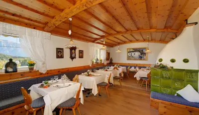 a restaurant with white tables and chairs and wooden ceilings at Hotel Dolomitenblick in Collalbo