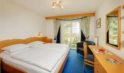 a bedroom with a bed and a desk and a window at Hotel Dolomitenblick in Collalbo
