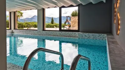 a swimming pool with a view of the mountains through windows at Die Sonne in Kaltern in Caldaro
