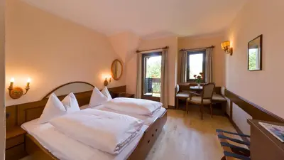 a bedroom with two beds and a table and window at Die Sonne in Kaltern in Caldaro