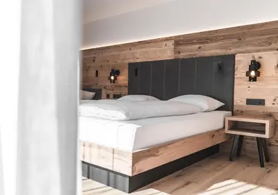 a bedroom with a large bed with a wooden headboard at Brunnerhof Klausen-Chiusa in Chiusa