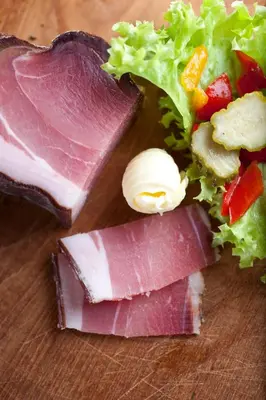 a piece of meat with lettuce and vegetables on a table at Brunnerhof Klausen-Chiusa in Chiusa