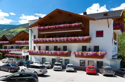 a large building with cars parked in a parking lot at Brunnerhof Klausen-Chiusa in Chiusa