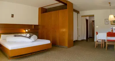 a hotel room with a bed and a dining room at Raschötzhof in Funes