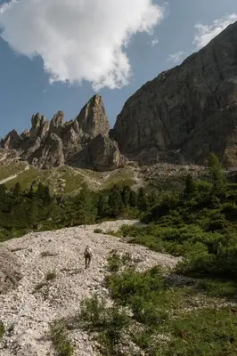 a person walking on a rocky hill with mountains in the background at Raschötzhof in Funes