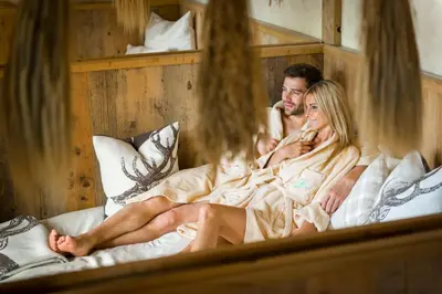 a man and a woman sitting on a bed at Andreus Resorts in San Leonardo in Passiria