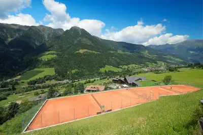 an orange building on a hill with mountains in the background at Andreus Resorts in San Leonardo in Passiria