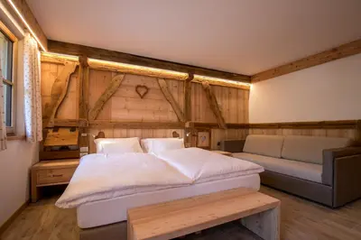 a bedroom with a large bed and a couch at Agriturismo Malga Piè in Soraga