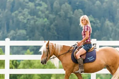 a young girl riding on the back of a horse at Hotel Sonnenalm in Saltusio
