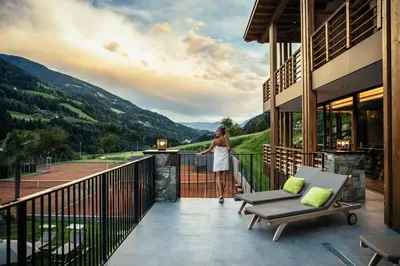 a woman standing on a balcony looking out at the mountains at Hotel Sonnenalm in Saltusio