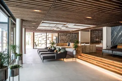 a living room with couches and tables and windows at Hotel Sonnenalm in Saltusio