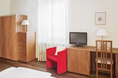 a room with a desk with a tv and a red chair at Hotel Sonnenhof in Merano