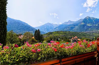 a garden with flowers and mountains in the background at Residence Neuhäuslhof in Merano