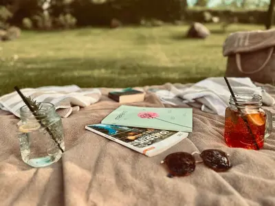 a picnic blanket with a cell phone and a book at Residence Neuhäuslhof in Merano