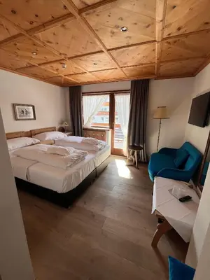 a bedroom with a large bed and a blue chair at Mountain Home Villa Anna in Selva di Val Gardena