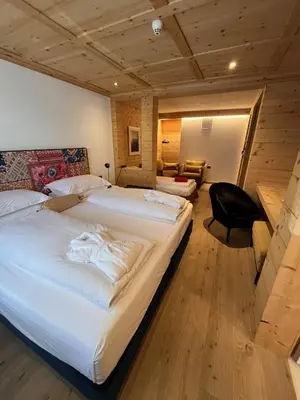 a hotel room with two beds and a chair at Mountain Home Villa Anna in Selva di Val Gardena