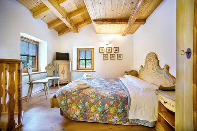 a bedroom with a bed with a wooden head board at Romantic Loft Sottoguda in Sottoguda