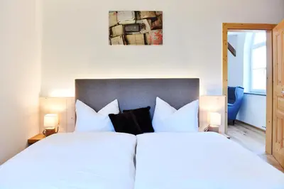 two beds in a bedroom with white sheets and pillows at Castel Campan in Bressanone